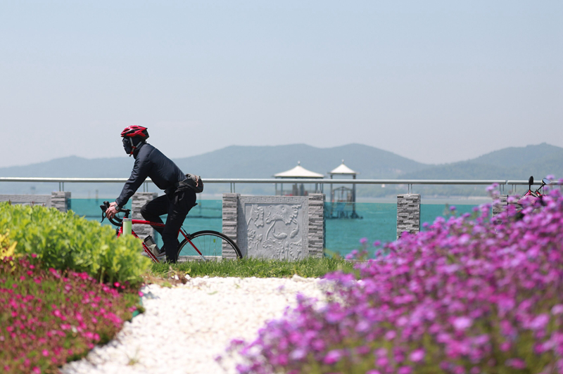 市民在風(fēng)景如畫的環(huán)湖路上騎行